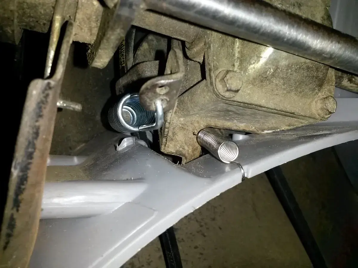 Jak założyć sprężynę napędu do kosiarki spalinowej? Nowa sprężyna jest gotowa do montażu, aby przywrócić sprawność mechanizmu.